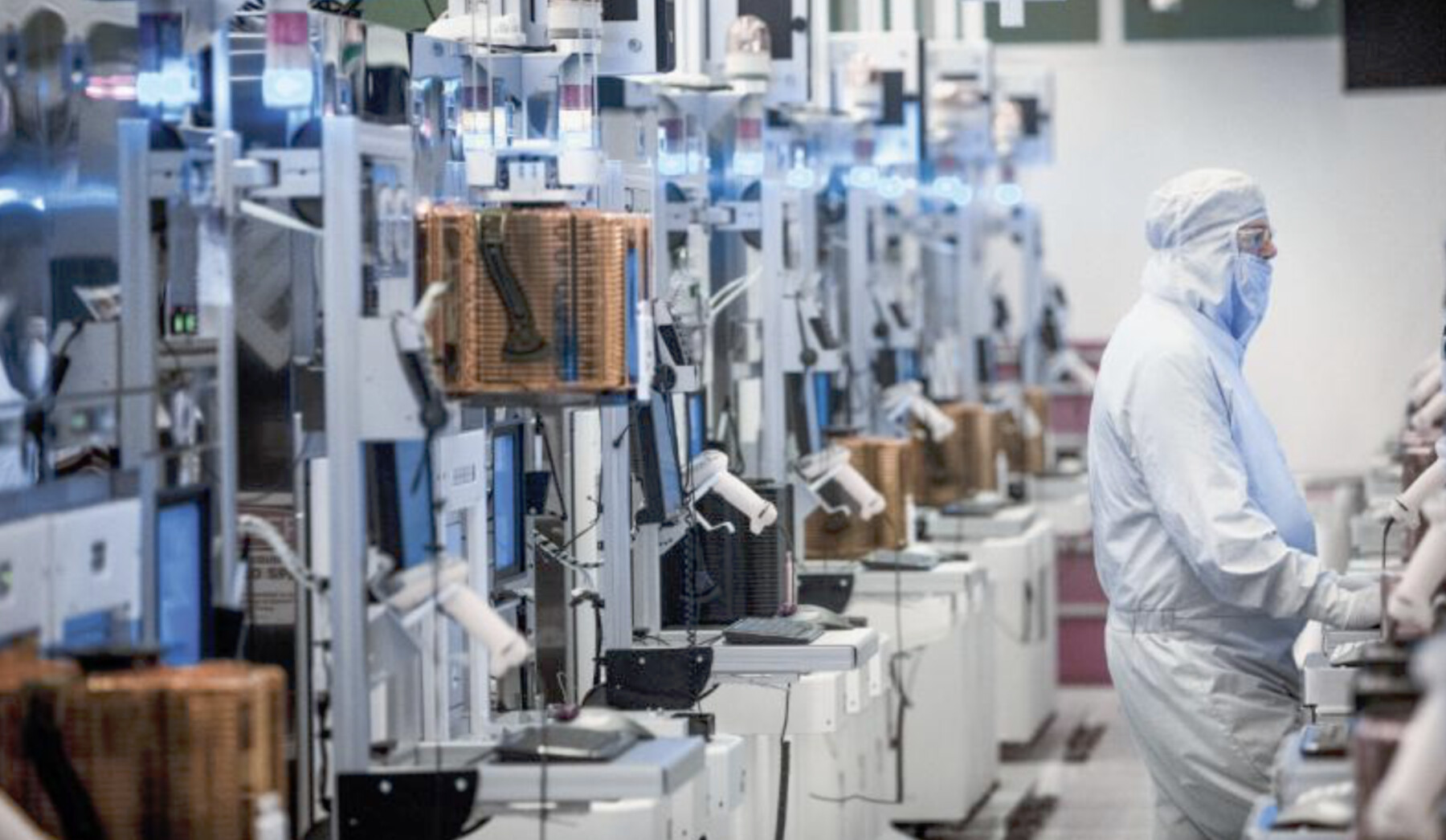 Semiconductor cleanroom with worker in full bunny suit operating advanced lithography equipment
